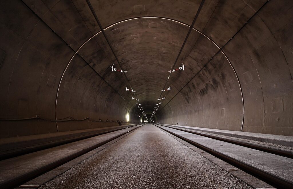 En tunnel med vägbana och takmonterade lampor sett rakt framifrån.