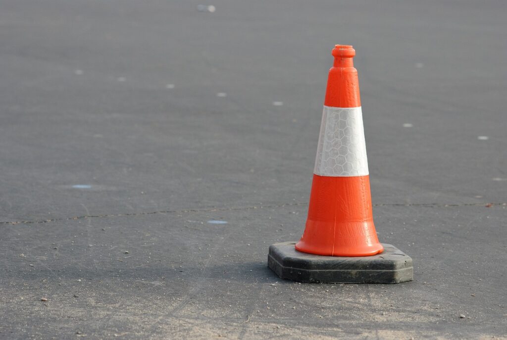 En orange trafikkon står på en asfalterad väg.
