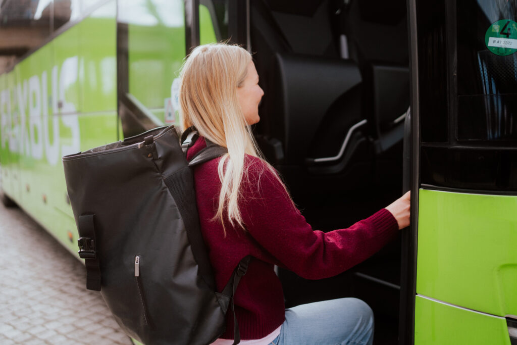 En resenär med ryggsäck kliver på en grön buss.