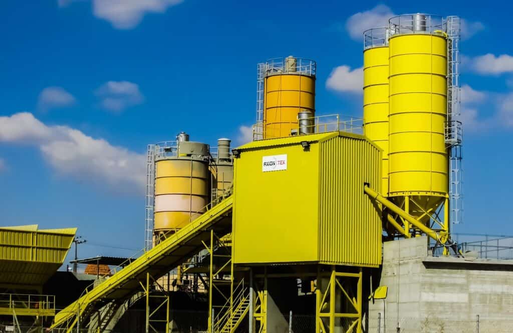 Gul betongfabrik med silos mot blå himmel.