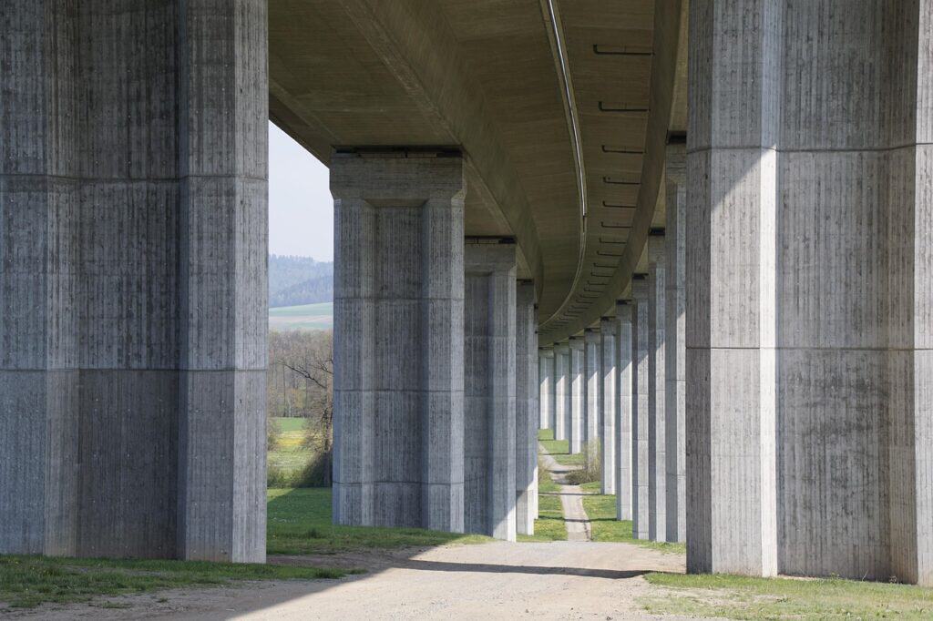 En motorvägsbro med kraftiga betongpelare sedd underifrån.