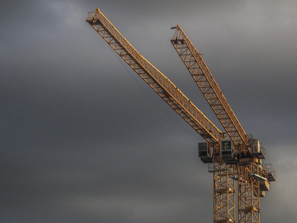 En byggkran vid en byggarbetsplats mot mörk himmel.