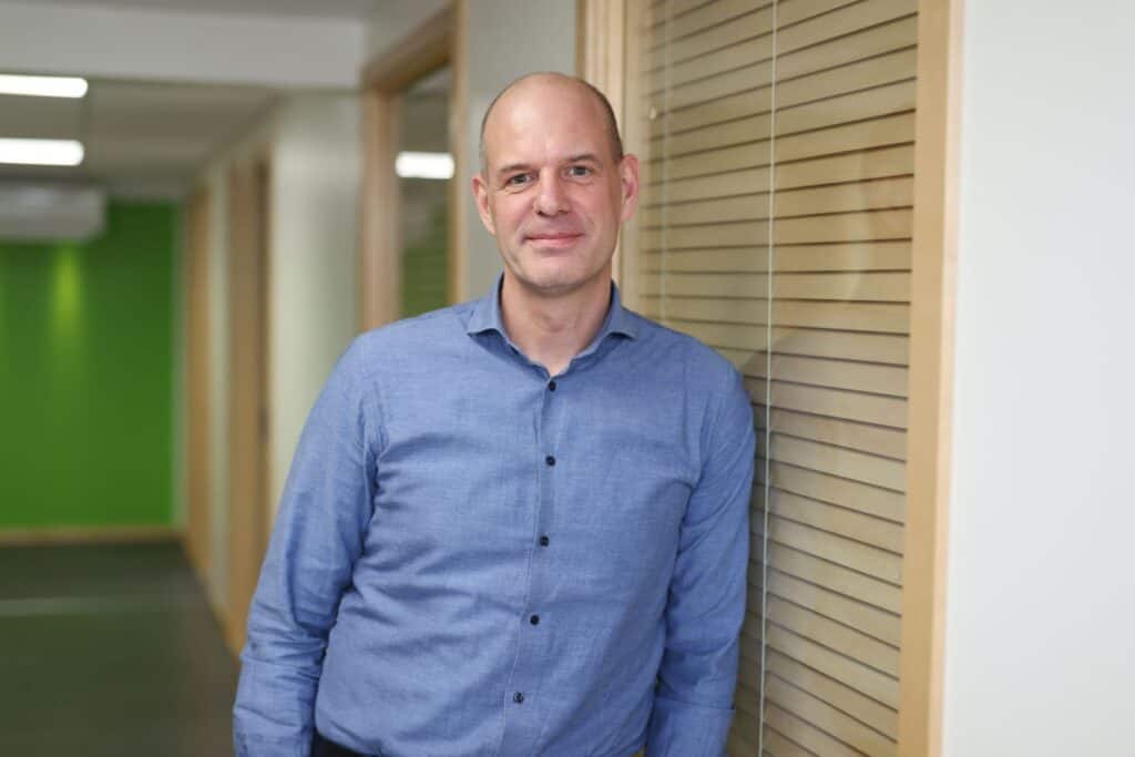 Leif Fransson står lutad mot en vägg i en kontorskorridor.